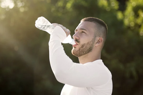 Young guy drinking water from bottle — Stock Photo, Image