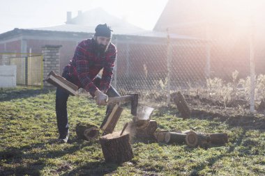 Sakallı oduncu ya da oduncu dışarıda baltayla odun ya da odun kesiyor..