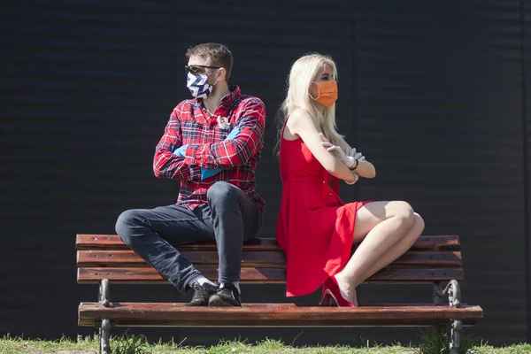 夫婦の疎外と剥離 彼らは保護マスクの距離とベンチに座っている — ストック写真
