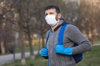 Koruyucu maskeli ve koruyucu eldivenli adam dışarıda, parkta..