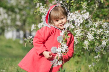 Açık havada bahar çiçekleri olan kırmızı paltolu şirin bir kız.. 