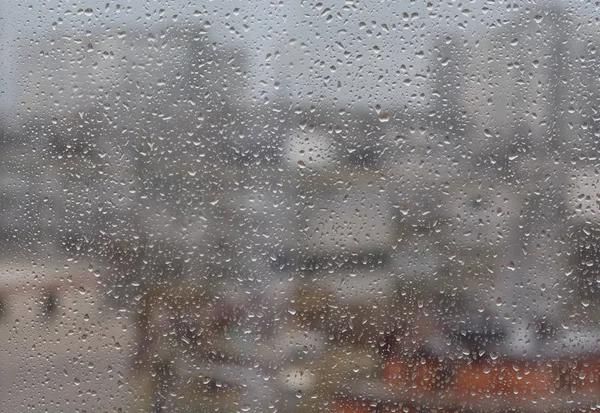 Lluvia cae en la ventana, fondo borroso againt de una ciudad —  Fotos de Stock