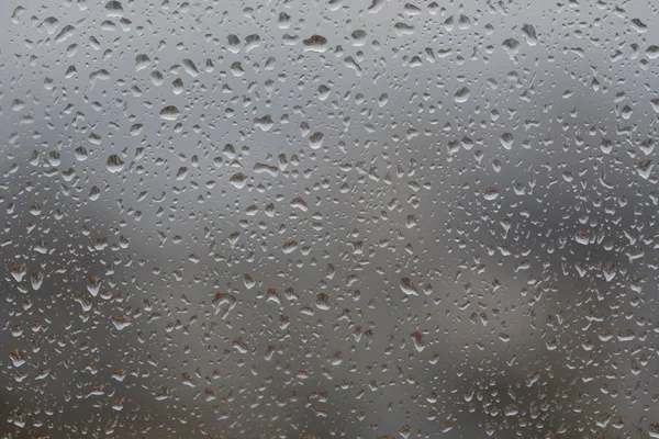 Regentropfen auf Fenster, vor verschwommenem Hintergrund einer Stadt — Stockfoto