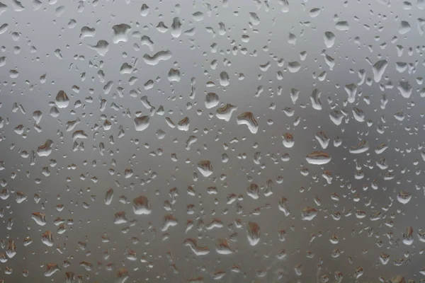 Rain drops on window, against blurry background of a town — Stock Photo, Image