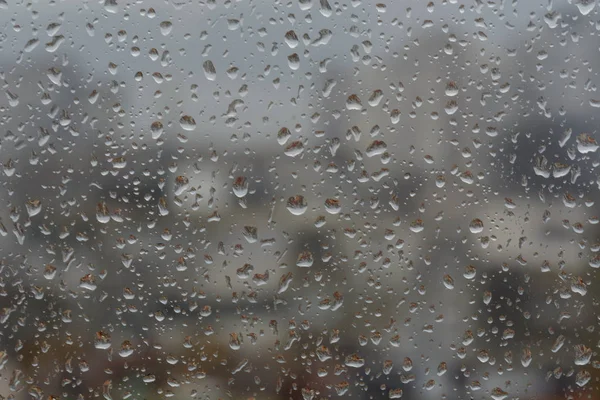 Regentropfen auf Fenster, vor verschwommenem Hintergrund einer Stadt — Stockfoto