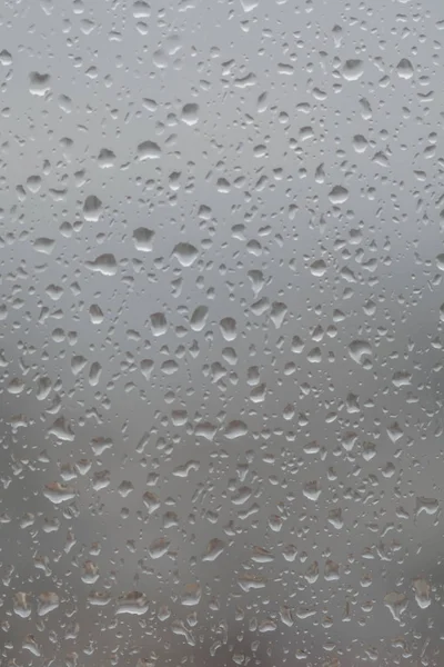 Lluvia cae en la ventana, sobre el fondo borroso de una ciudad —  Fotos de Stock