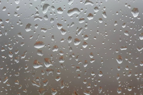 Lluvia grande cae sobre la ventana, sobre el fondo borroso de una ciudad —  Fotos de Stock