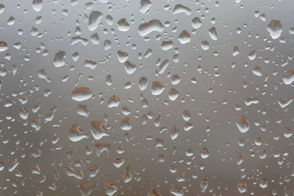 Chuva grande cai na janela, contra o fundo embaçado de uma cidade — Fotografia de Stock