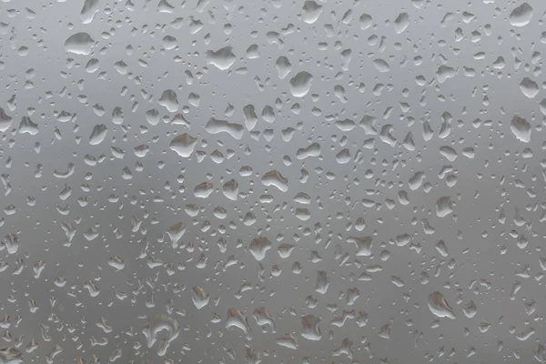Chuva cai na janela, contra o fundo embaçado de uma cidade — Fotografia de Stock