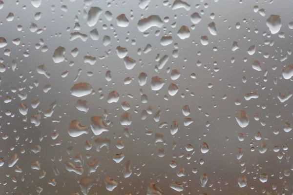 Große Regentropfen auf Fenster, vor verschwommenem Hintergrund einer Stadt — Stockfoto