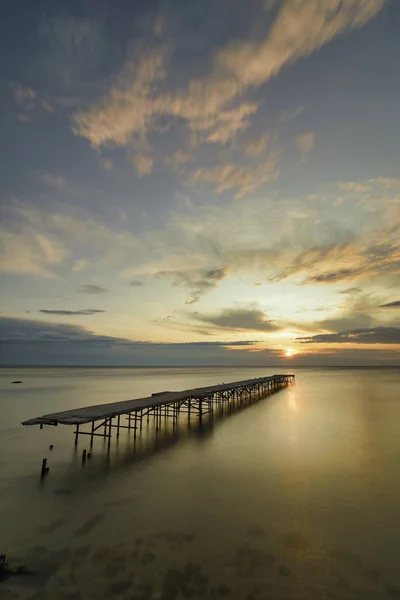 Ponte rotto in calcestruzzo nel mare contro un'alba vibrante in V — Foto Stock