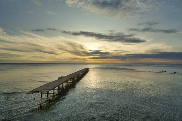 Puente roto de hormigón en el mar contra un vibrante amanecer en V — Foto de Stock