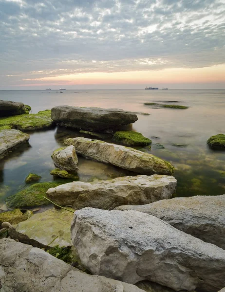 Pedras com algas como o nascer do sol contra um amarelo vibrante e oran — Fotografia de Stock