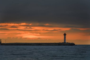 bir deniz feneri gündoğumu canlı turuncu gökyüzü karşı deniz manzarası