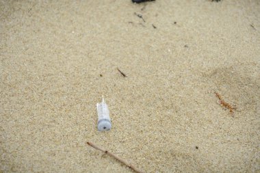 Plastik şırınga ve diğer plastik çöp ile sahilde.