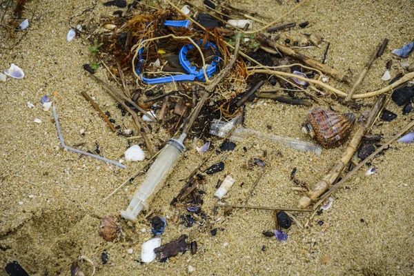 Plast på stranden med spruta och andra plast sopor. — Stockfoto