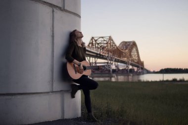 köprünün diğer tarafında r dibinde bir gitar konumu olan kız