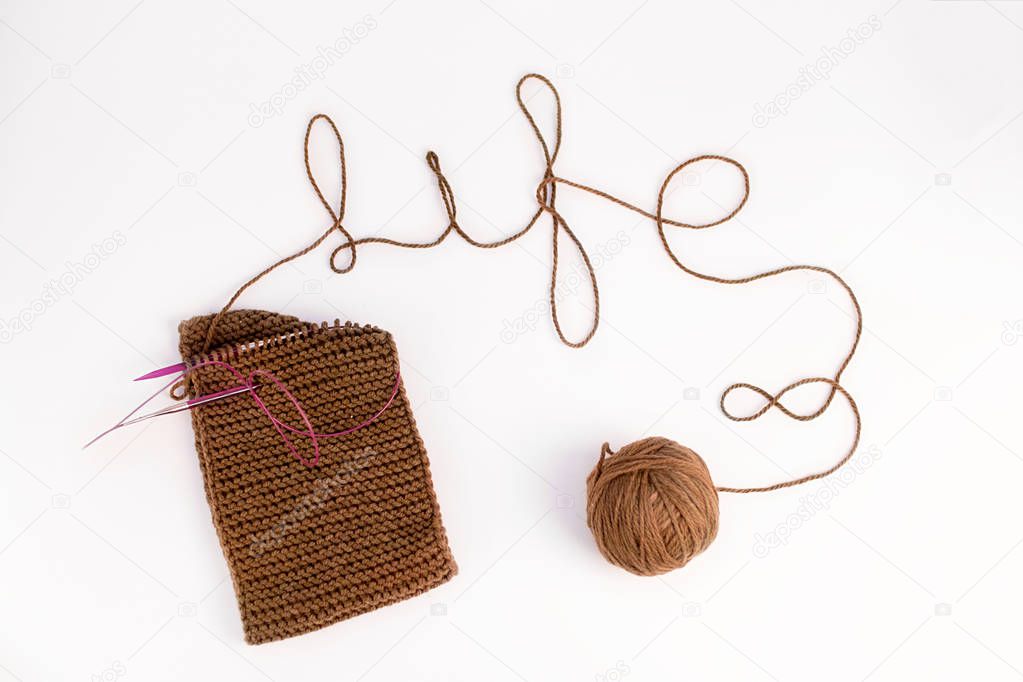 knitted scarf of brown thread and a ball on a white background
