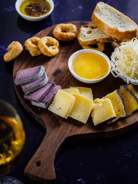 Vue rapprochée de fromages variés, sauce et pain sur planche à découper en bois — Photo de stock