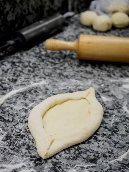 Vue rapprochée de la pâte crue pour khachapuri géorgien traditionnel et rouleau à pâtisserie en bois sur la table — Photo de stock