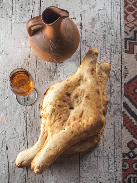 Vista superior de saborosos pães tradicionais georgianos, vidro com bebida e jarro de barro na mesa — Fotografia de Stock