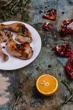 delicious grilled chicken legs with pomegranade seeds and orange on concrete surface clipart