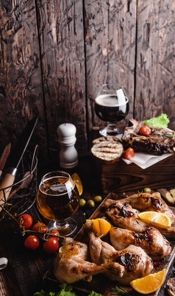 вкусное мясо на гриле с овощами и пивом на деревянном фоне
