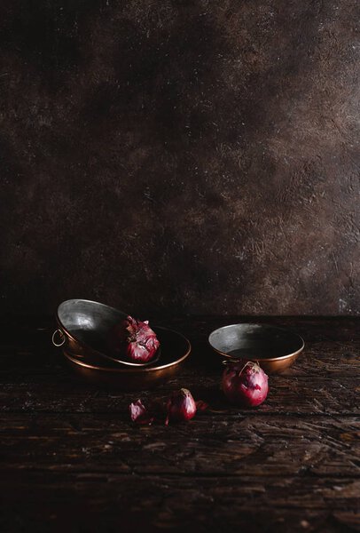 close-up view of vintage utensils with red onions on rustic wooden table 