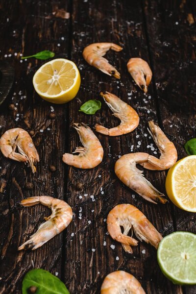 close-up view of delicious shrimp with citrus fruits and basil leaves on rustic wooden table   