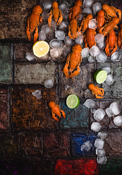 top view of delicious lobsters with ice cubes and citrus fruits on brick wall surface    