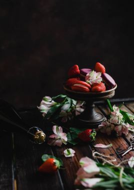 macarons ve çiçek ve şampanya şişesi ile ahşap masa üzerinde çilek ile Sevgililer günü için kase