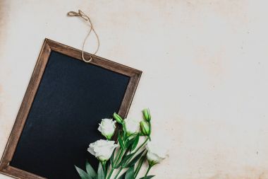 top view of blackboard in wooden frame with eustoma flowers on shabby background