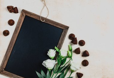 blackboard eustoma çiçek ve çikolata şekerleme ile ahşap çerçeve içinde üstten görünüm