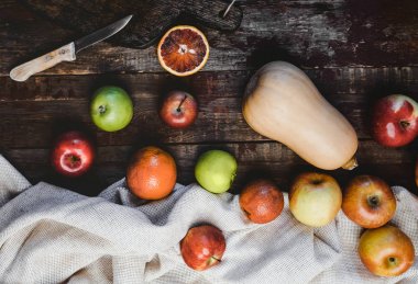 ahşap masa üzerinde kabak, elma, kan portakal, mutfak havlusu ve bıçağı Üstten Görünüm 