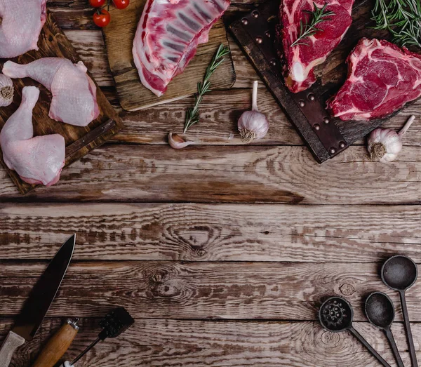 Top view of various raw meat and kitchen utensils on wooden table — Stock Photo