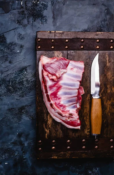 Vue du dessus des côtes de bœuf crues sur planche de bois avec couteau — Photo de stock