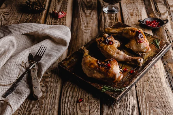 Close-up de deliciosas pernas de frango grelhadas em tábua de madeira com talheres — Fotografia de Stock