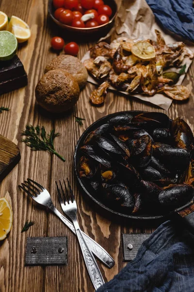 Pesce cotto assortito con pane e pomodori sul tavolo di legno — Foto stock