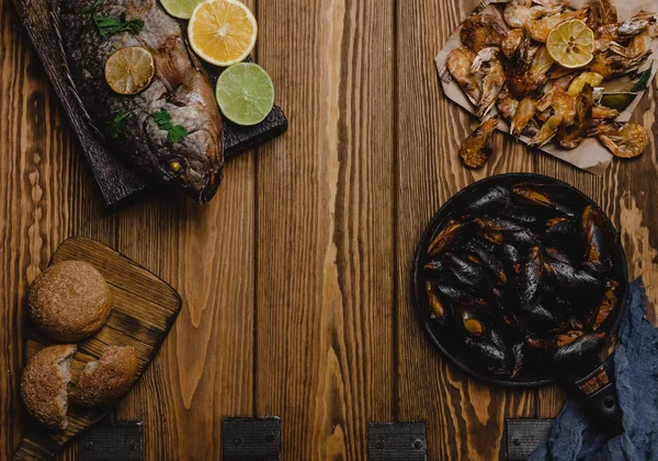 Top view of assorted seafood and baked fish with bread on wooden table — Stock Photo