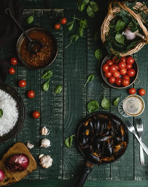 Top view of cooked mussels with shells served in pan with tomatoes, herbs and wine on rustic table — Stock Photo