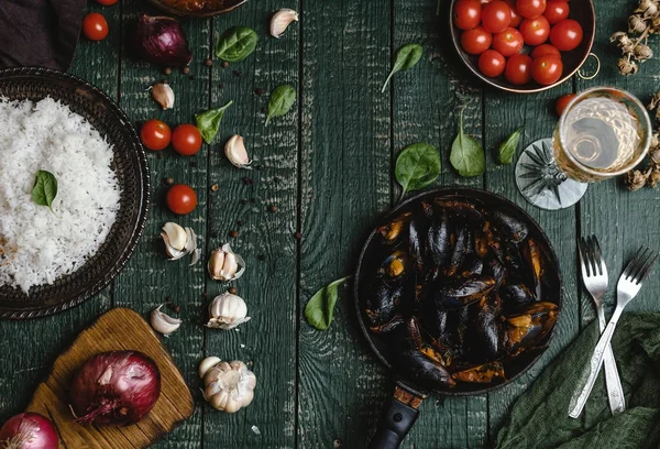 Vista dall'alto delle cozze cotte con conchiglie servite in padella con pomodori, erbe aromatiche e vino sulla tavola di legno — Foto stock