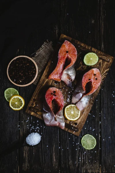 Вид зверху на свіжу нарізану червону рибу зі спеціями та скибочками цитрусових на сільському дерев'яному столі — стокове фото