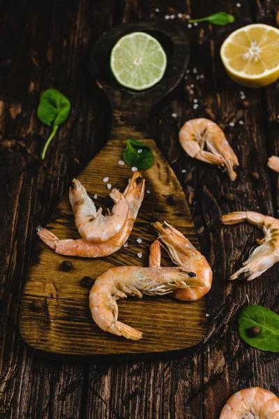 Close-up view of delicious shrimp with citrus fruits on rustic wooden table — Stock Photo