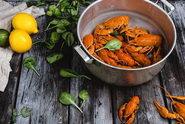 Close-up view of delicious lobsters in pan and herbs with citrus fruits on rustic wooden table — Stock Photo