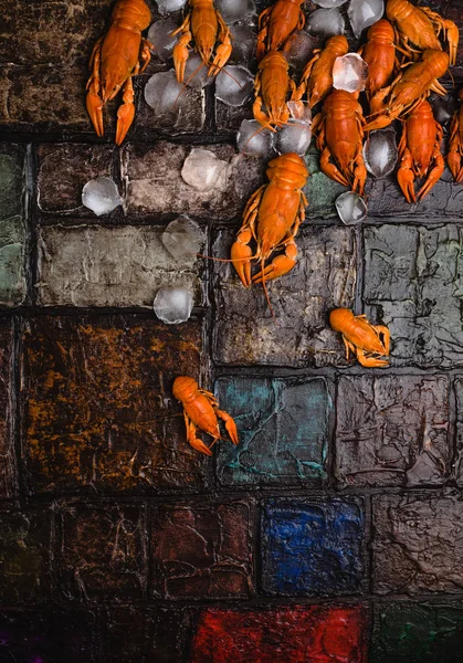 Close-up view of gourmet lobsters with ice cubes on brick wall surface — Stock Photo