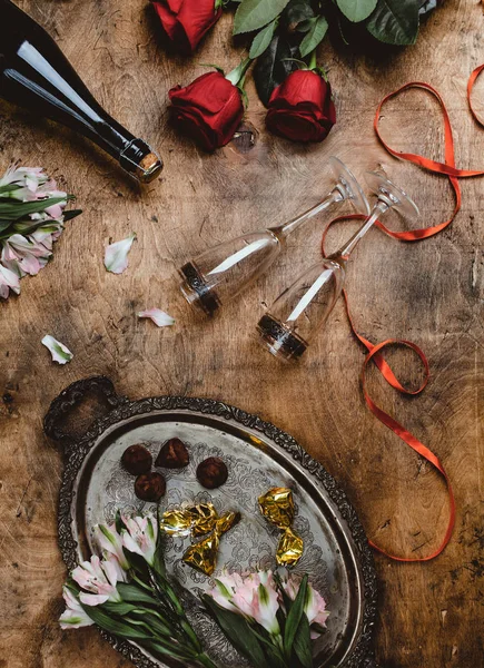 Top view of flowers, champagne bottle, glasses and chocolate candies on wooden table, valentines day concept — Stock Photo