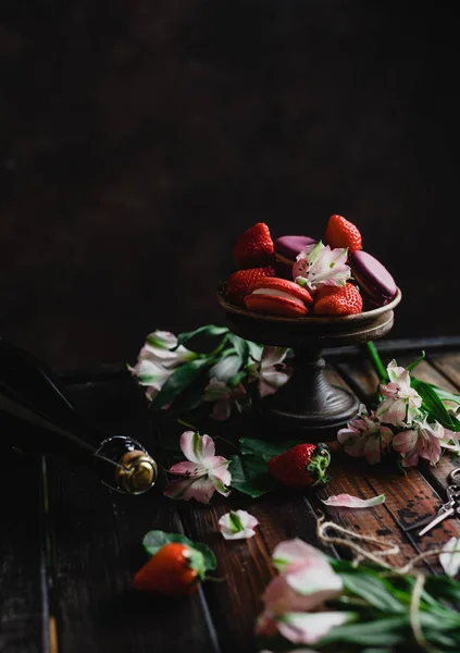 Чаша с макаронами и клубникой на деревянном столе с цветами и бутылкой шампанского на день Святого Валентина — стоковое фото