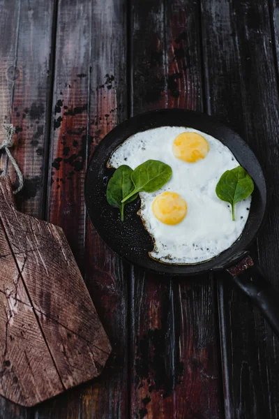 Top view of fried eggs with spinach on wooden tabletop — Stock Photo