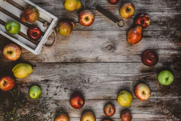 Draufsicht auf Holzkiste, Handwaagen, Äpfel und Birnen auf rustikalem Tisch — Stockfoto