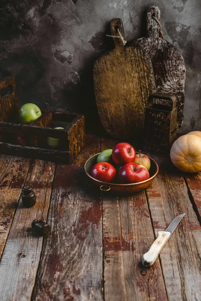 Planches à découper, râpe, citrouille, assiette aux pommes et couteau sur table en bois — Photo de stock